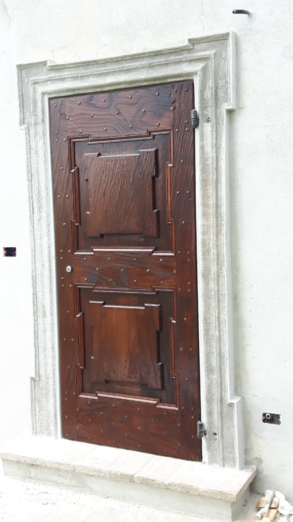 Portone antico in legno restaurato conservando ferramenta e segni del tempo
